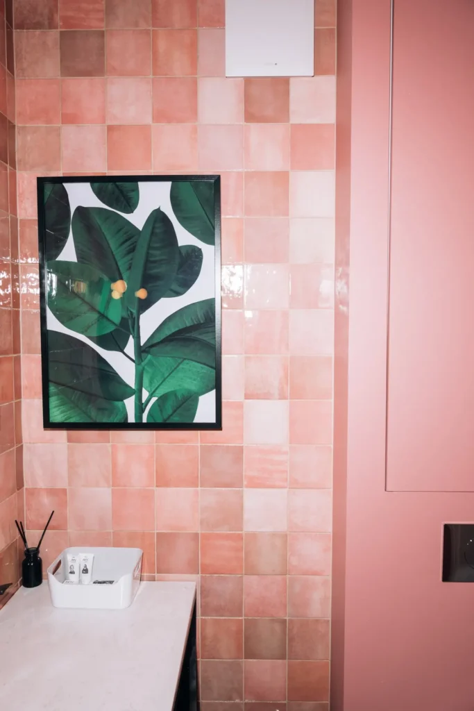 Pudrowo różowe drzwi i różowe płytki w różnych odcieniach w połączeniu z roślinami